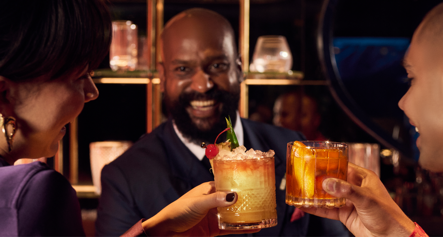 Barman smiling at two women with cocktails